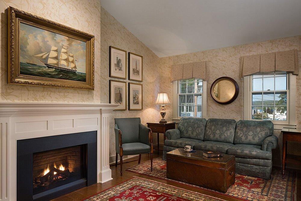 Cozy living room with a lit fireplace, sofa, paintings, and a vintage lamp.