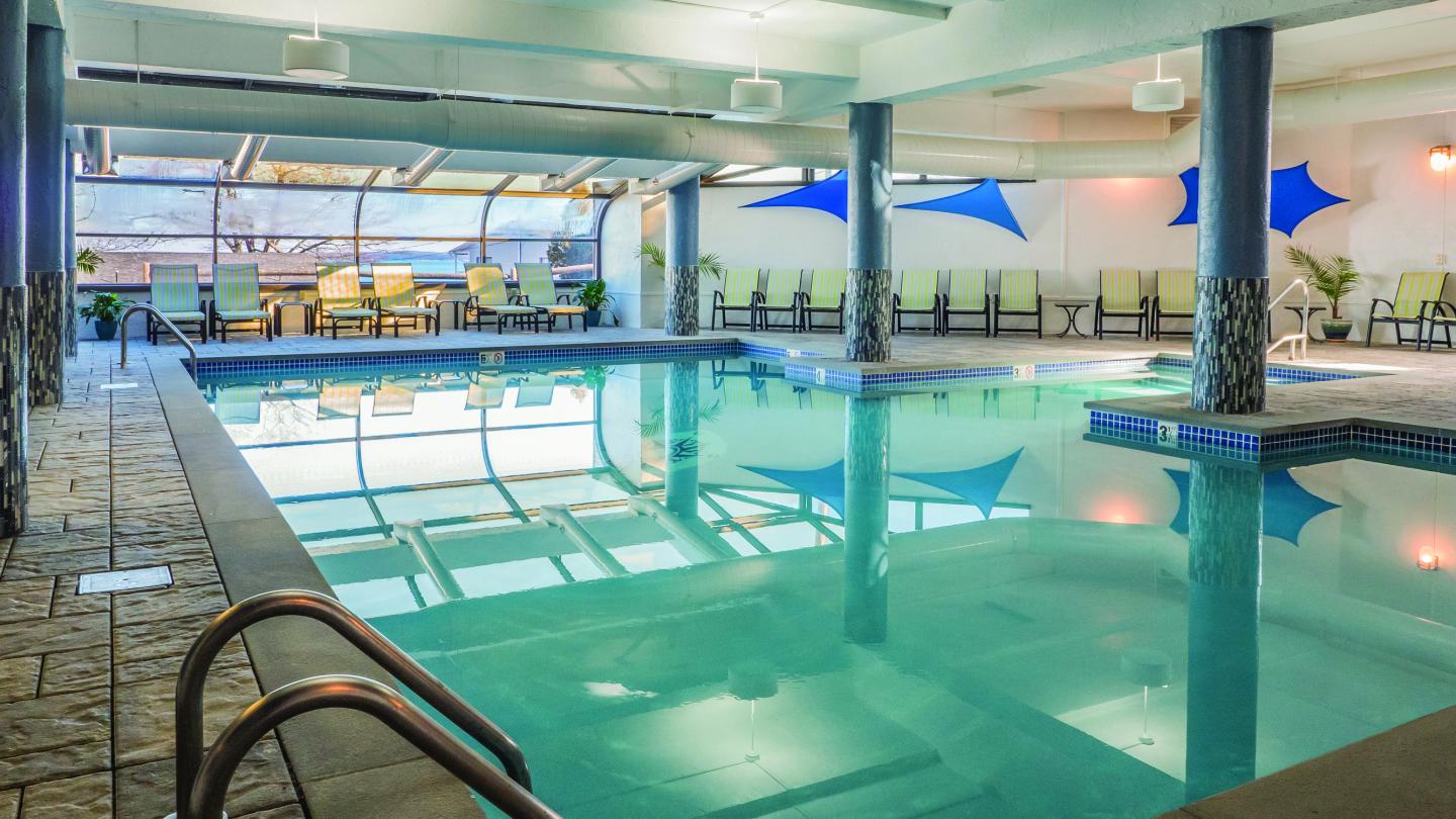 Indoor pool with lounge chairs, large windows, and blue wall accents.