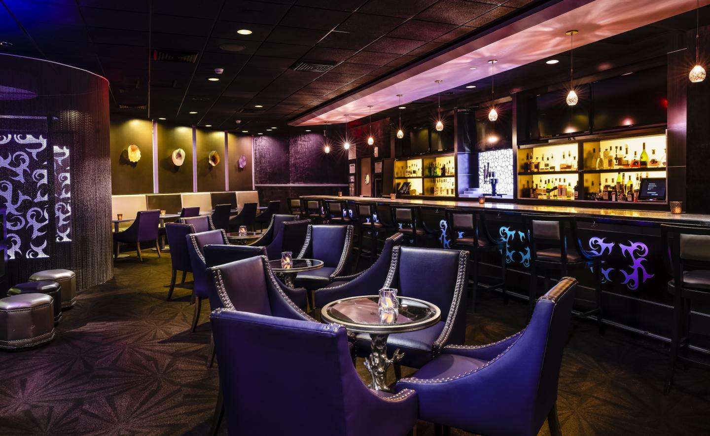 Dimly lit lounge with purple chairs and bar counter.
