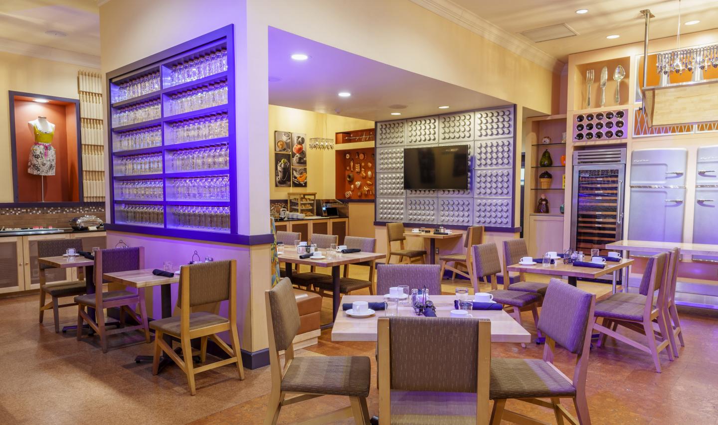 Cozy restaurant with wooden tables, purple lighting, and a wall-mounted TV.