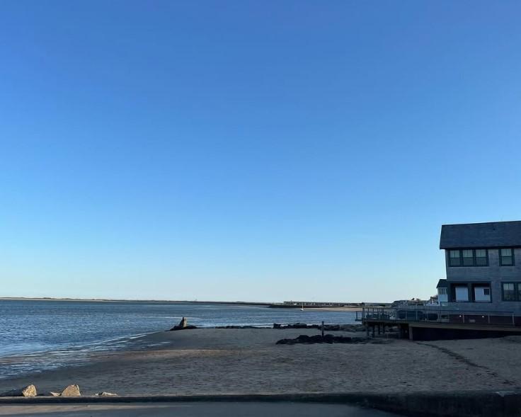 Beach with clear sky and a house by the water.