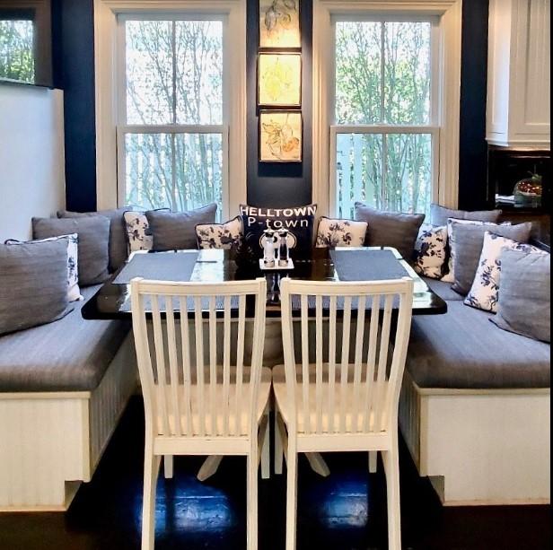 Dining nook with gray cushions, white chairs, and two large windows.