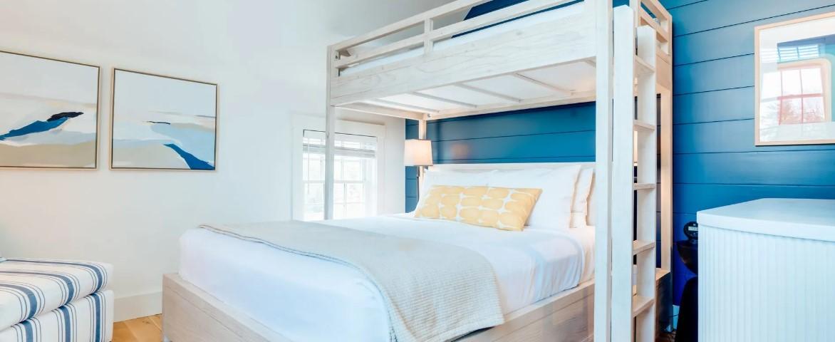 Bright bedroom with bunk bed, blue accent wall, and coastal decor.