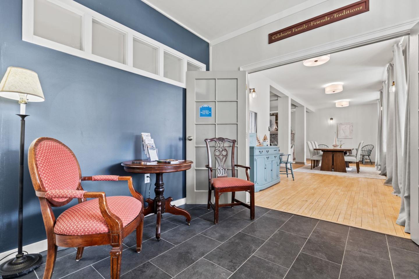 Lobby area with red chairs, blue wall, and open doorway to a bright hall.