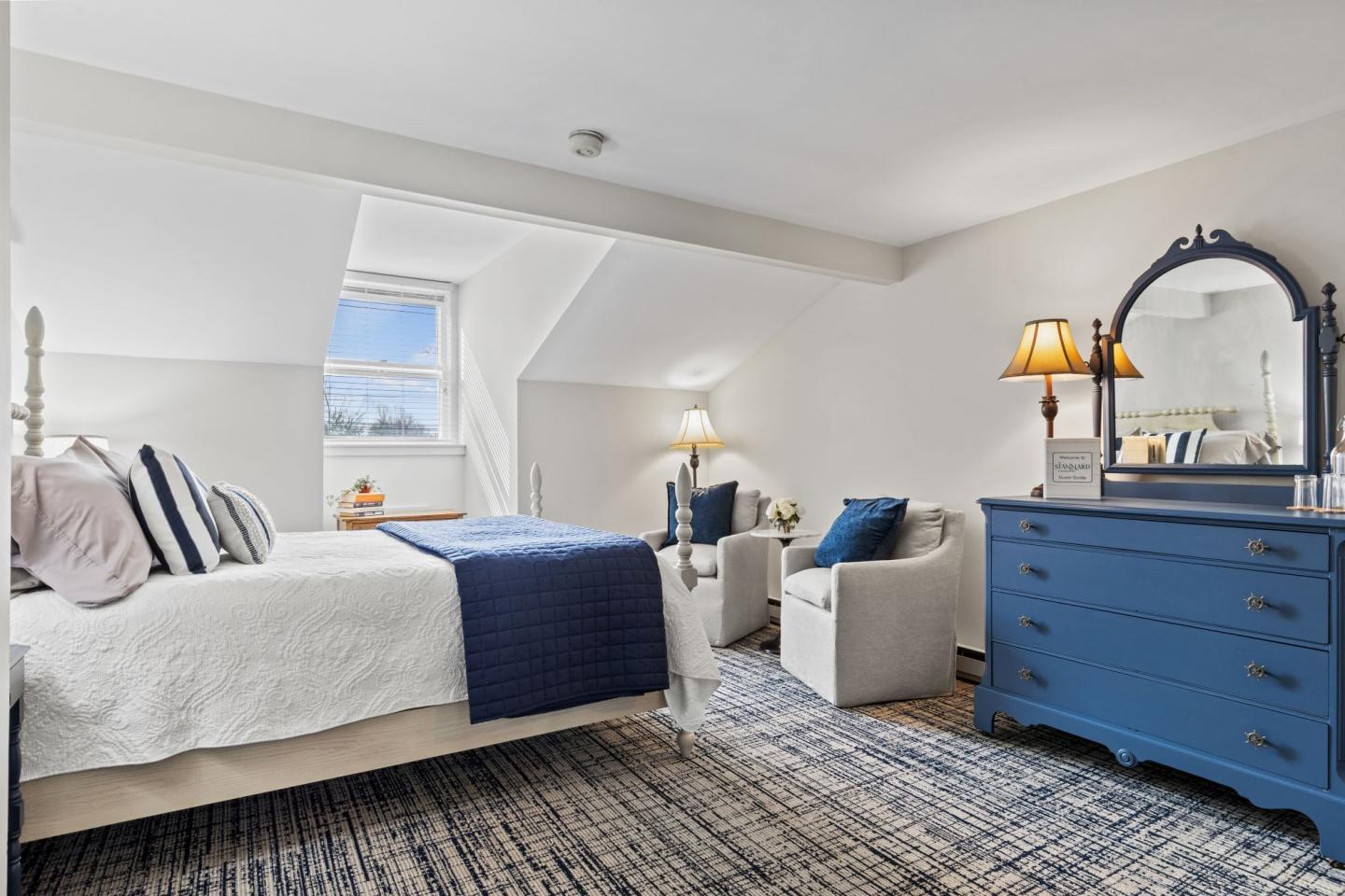 Cozy bedroom with white walls, blue accents, and a blue dresser.
