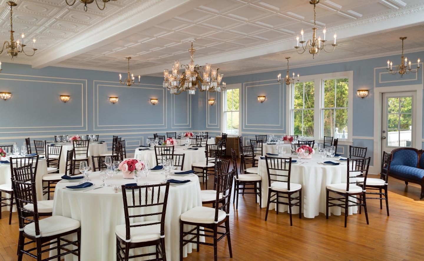 Elegant ballroom with round tables, white tablecloths, and pink floral centerpieces.