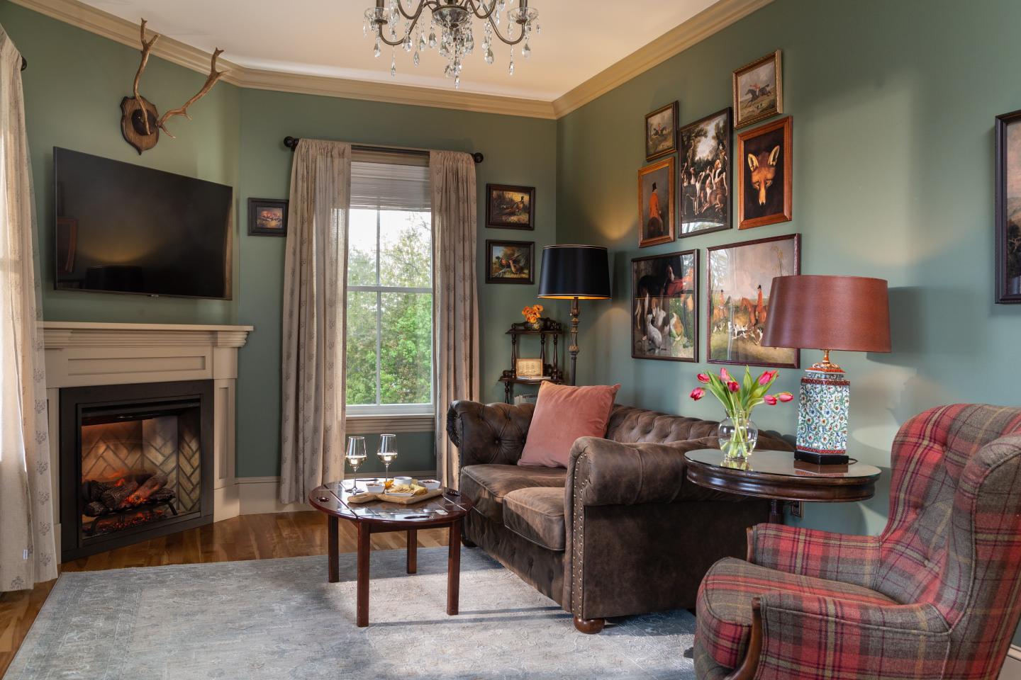 Cozy living room with fireplace, green walls, and elegant decor.