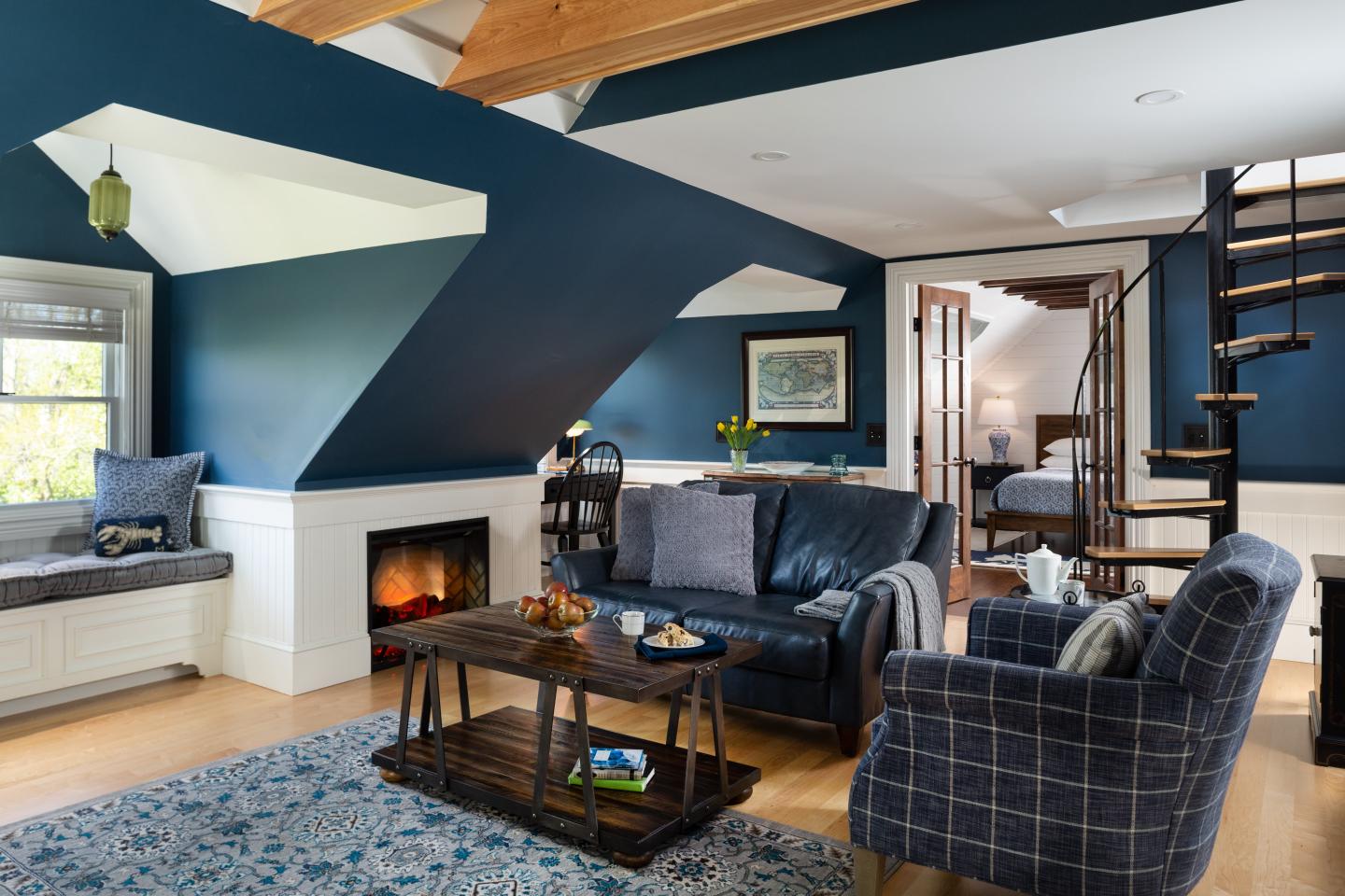 Cozy living room with blue walls, fireplace, and spiral staircase.