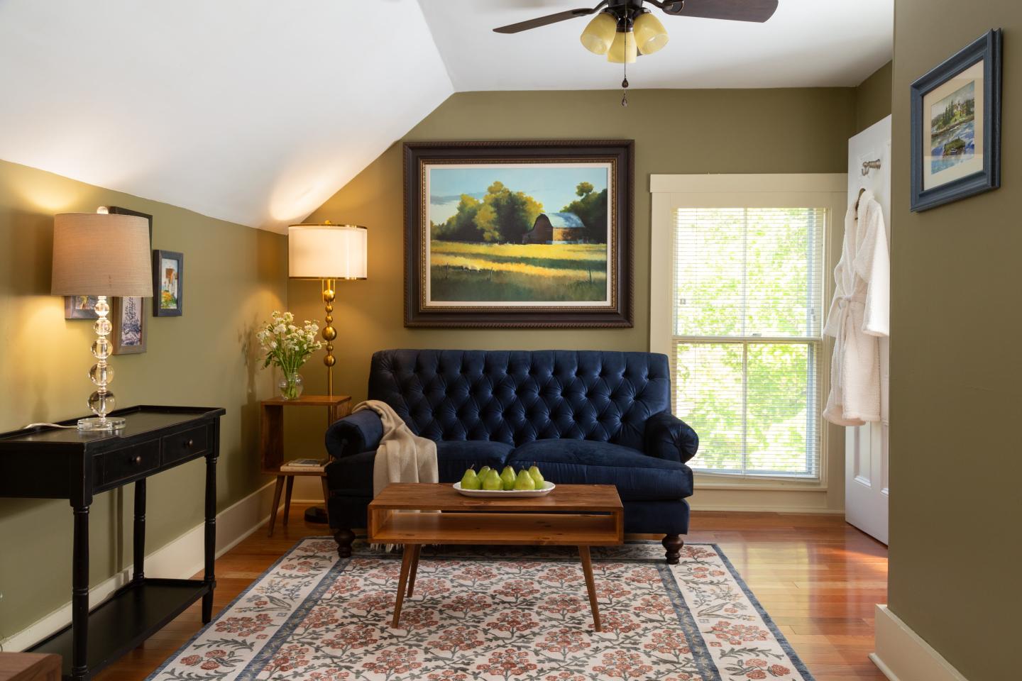 Cozy living room with blue sofa, painting, and wooden coffee table on a patterned rug.