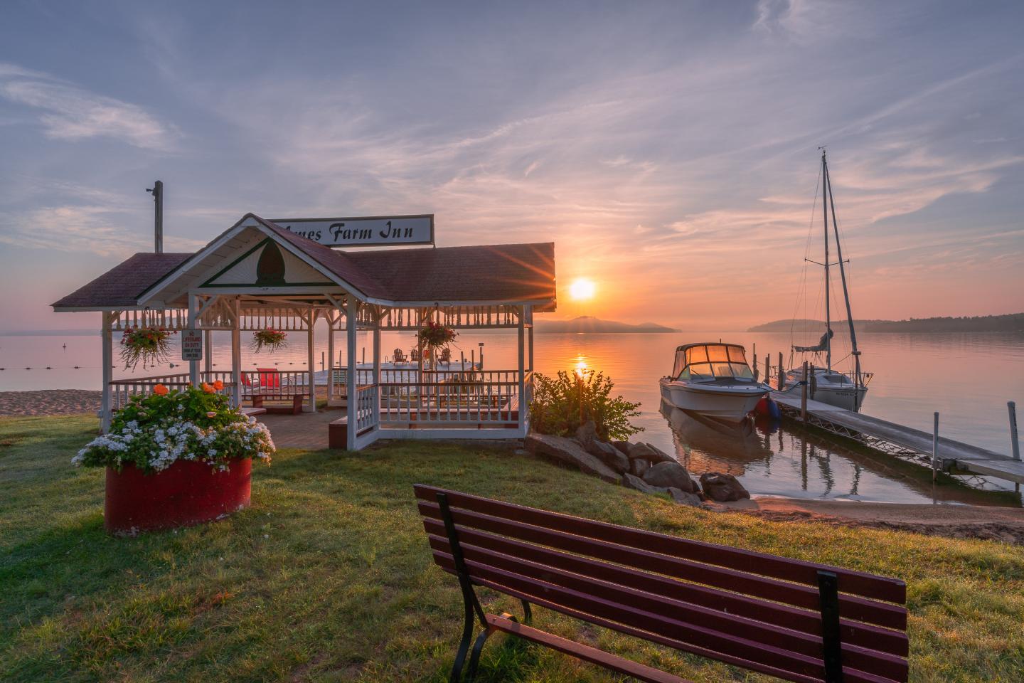 Gazebo by calm lake at sunrise.