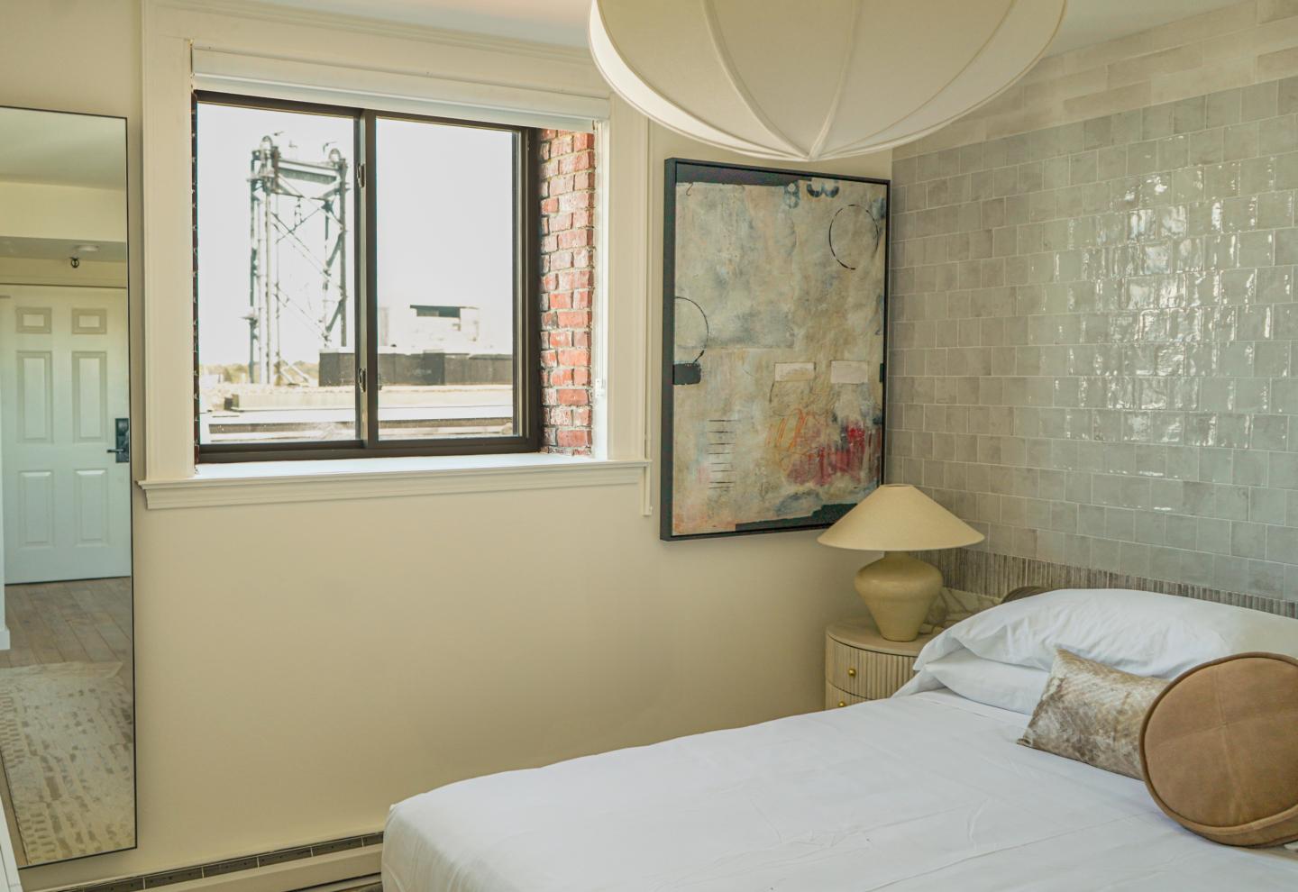 Cozy bedroom with a bed, abstract painting, and large window.