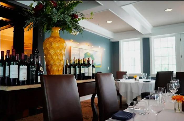 Elegant restaurant interior with wine display and set tables.
