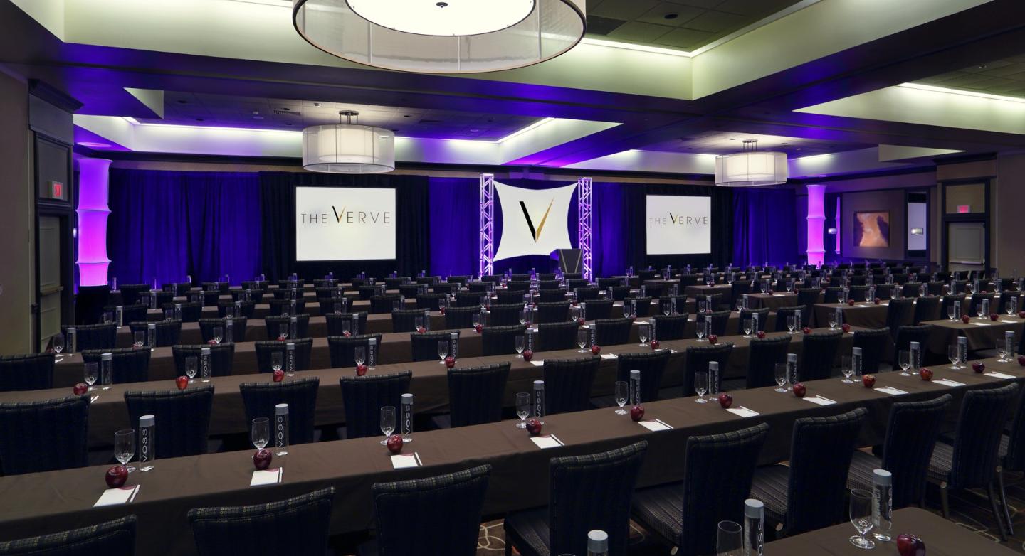 Conference room with rows of tables and purple lighting.
