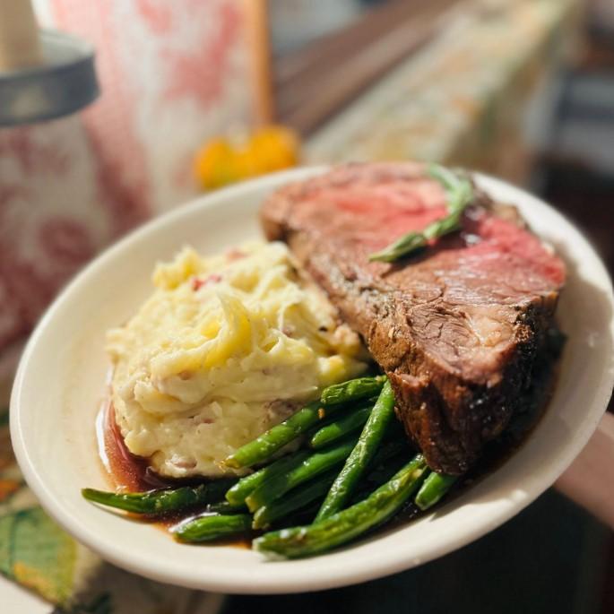 Mashed potatoes, steak, and green beans on a white plate.