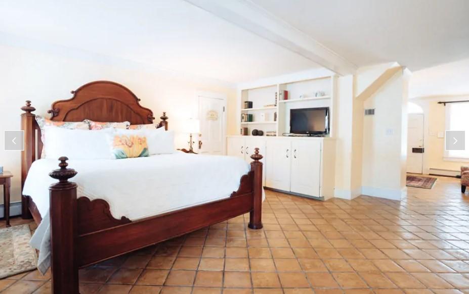 Spacious bedroom with wooden bed, white linens, and built-in shelves.