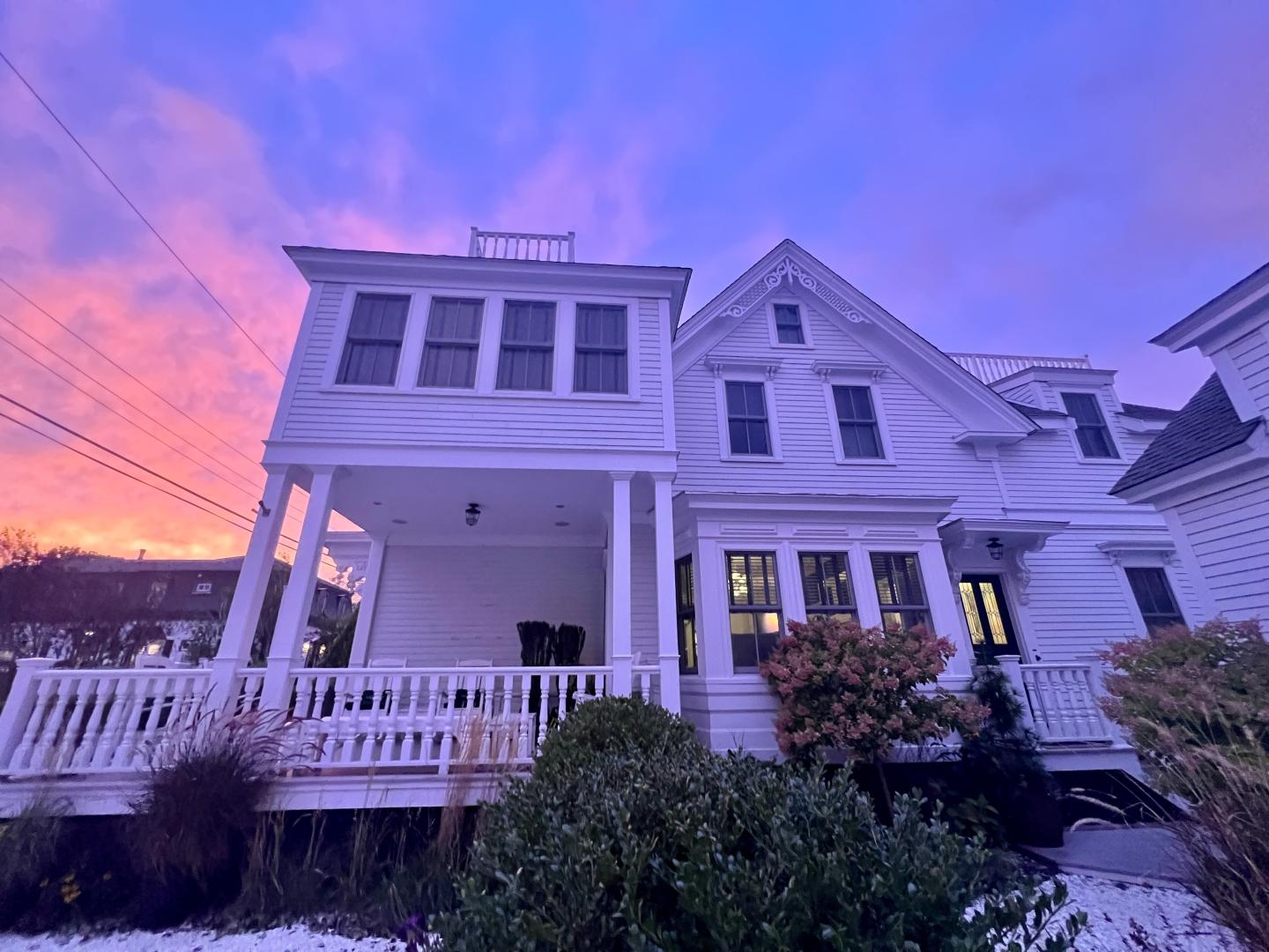 Large white house at sunset with pink and purple sky.usk