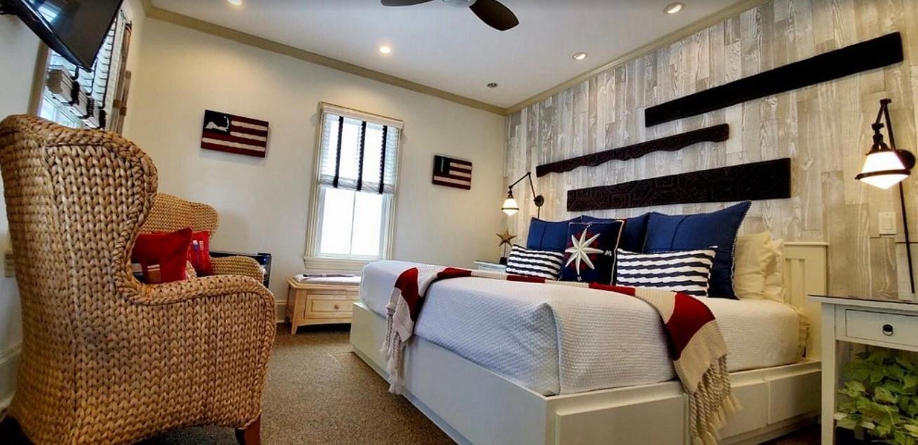 Cozy bedroom with nautical décor, blue pillows, and rustic wood walls.