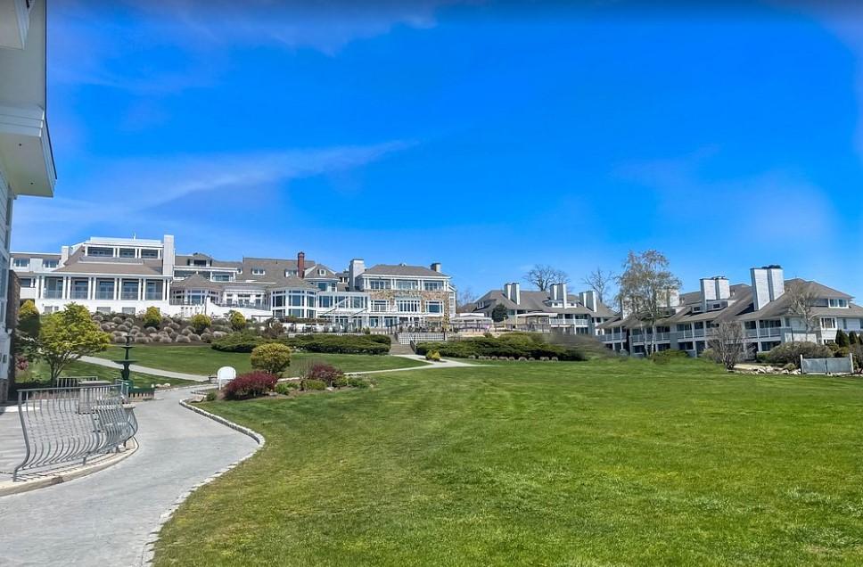 Expansive green lawn leading to large buildings under a blue sky.