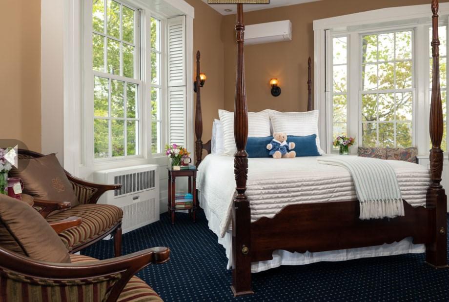 Cozy bedroom with a four-poster bed, large windows, and armchair.