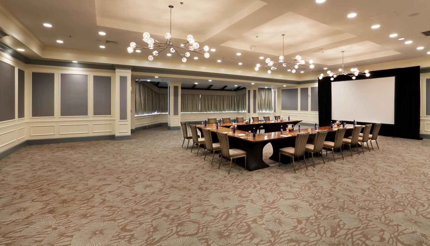 Elegant conference room with a long table, chairs, and a large screen.