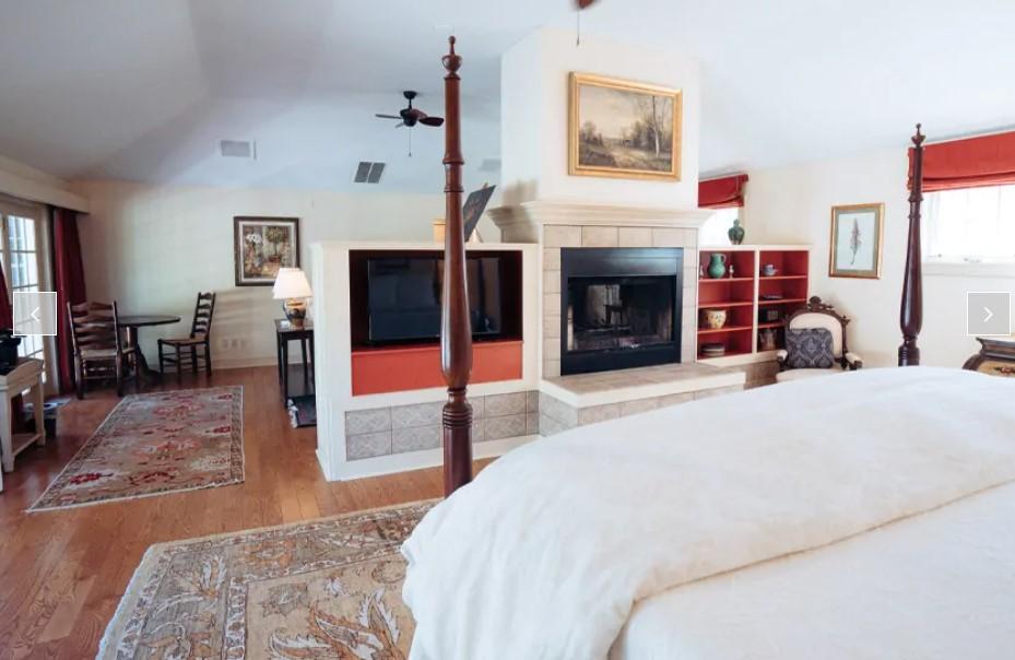 Spacious bedroom with a fireplace, large bed, and hardwood floor.