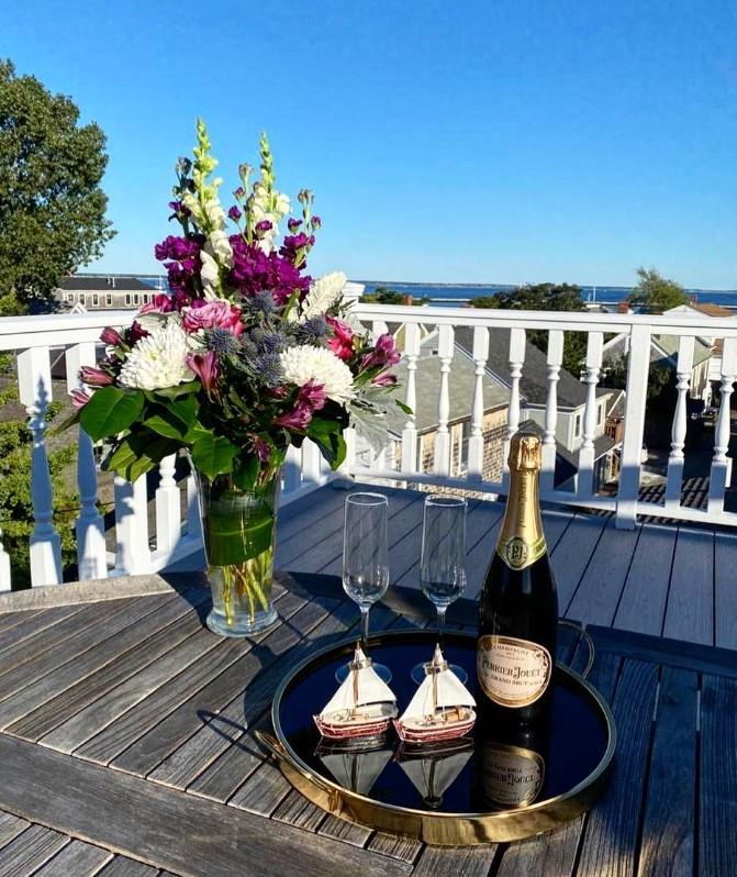 Vase of flowers and champagne on a sunny rooftop deck.