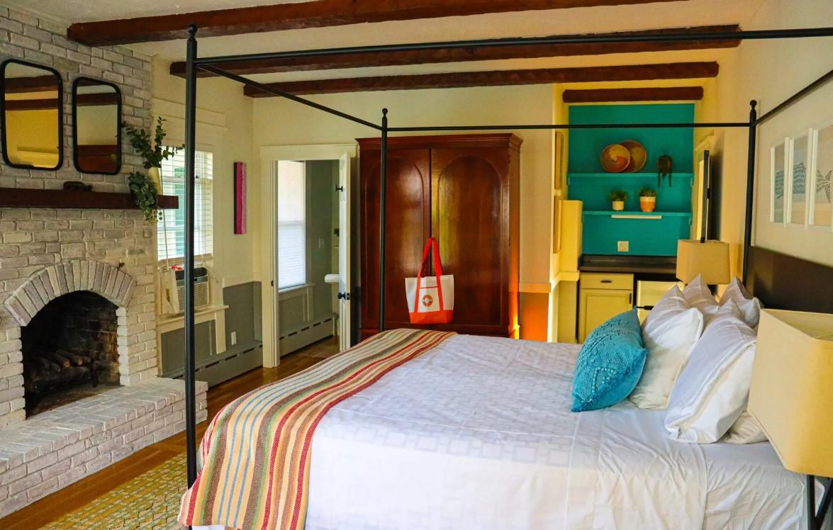 Cozy bedroom with four-poster bed, fireplace, and colorful decor.