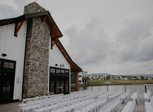 Modern venue exterior with stone accents and rows of white chairs under a cloudy sky.