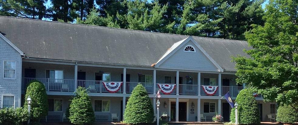 Two-story building with festive bunting and surrounded by trees.