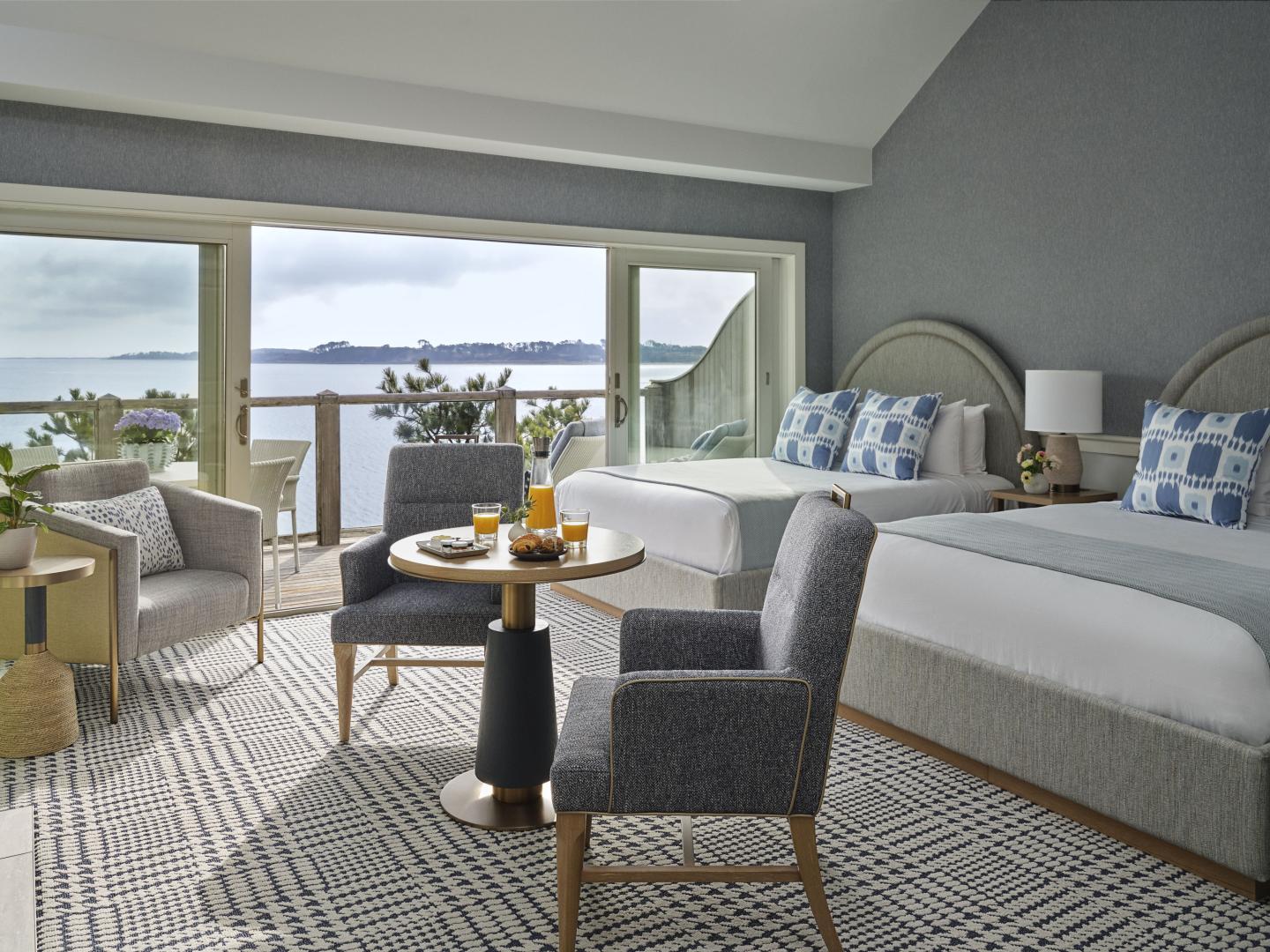 Luxurious hotel room with a sea view, two beds, and seating area.