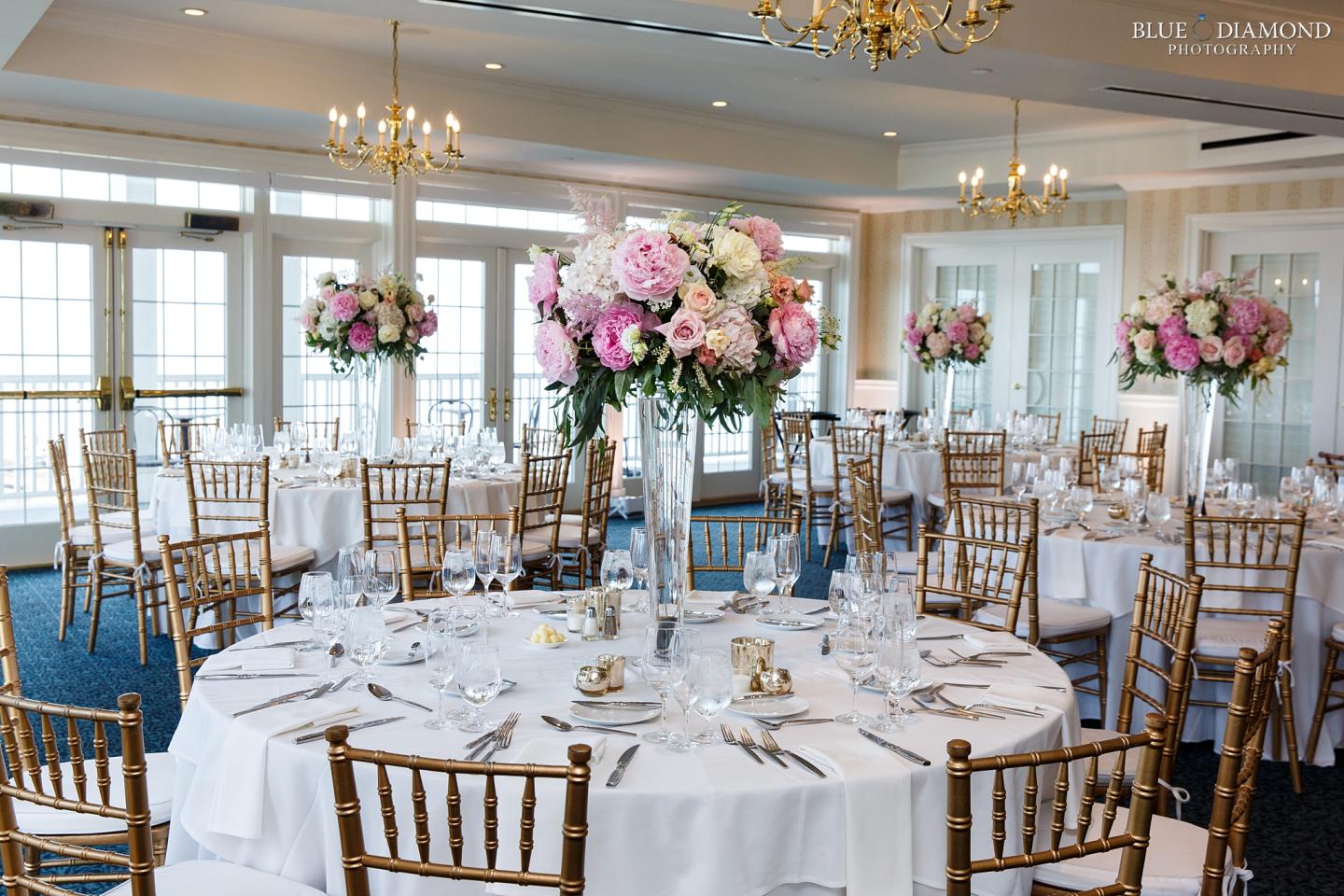 Elegant wedding reception with round tables, white linens, and pink floral centerpieces.
