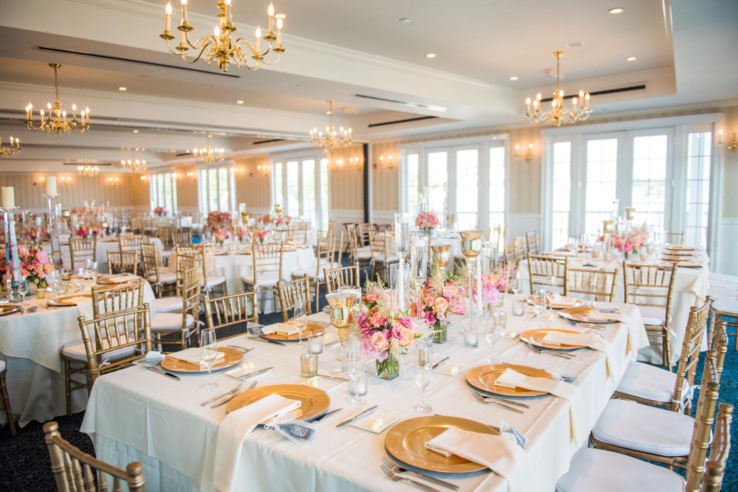 Elegant banquet hall with decorated tables and golden chairs.