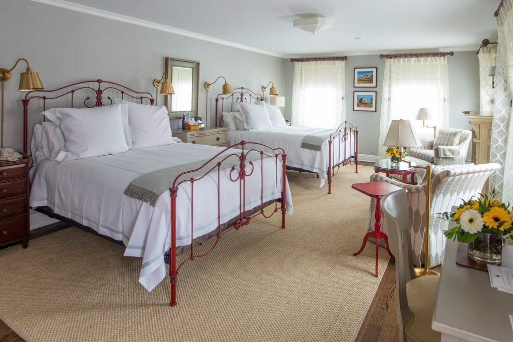 Cozy bedroom with two beds, light decor, and a table with sunflowers.