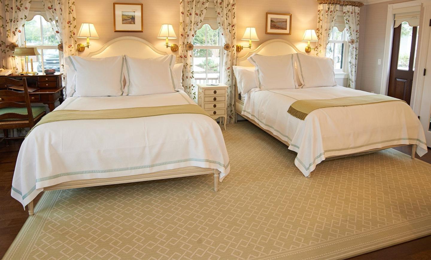 Two neatly made beds in a cozy, warmly lit bedroom.