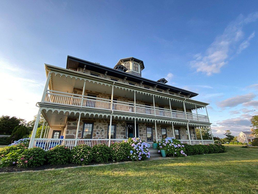 Victorian-style house with multiple balconies, surrounded by grass and flowers.