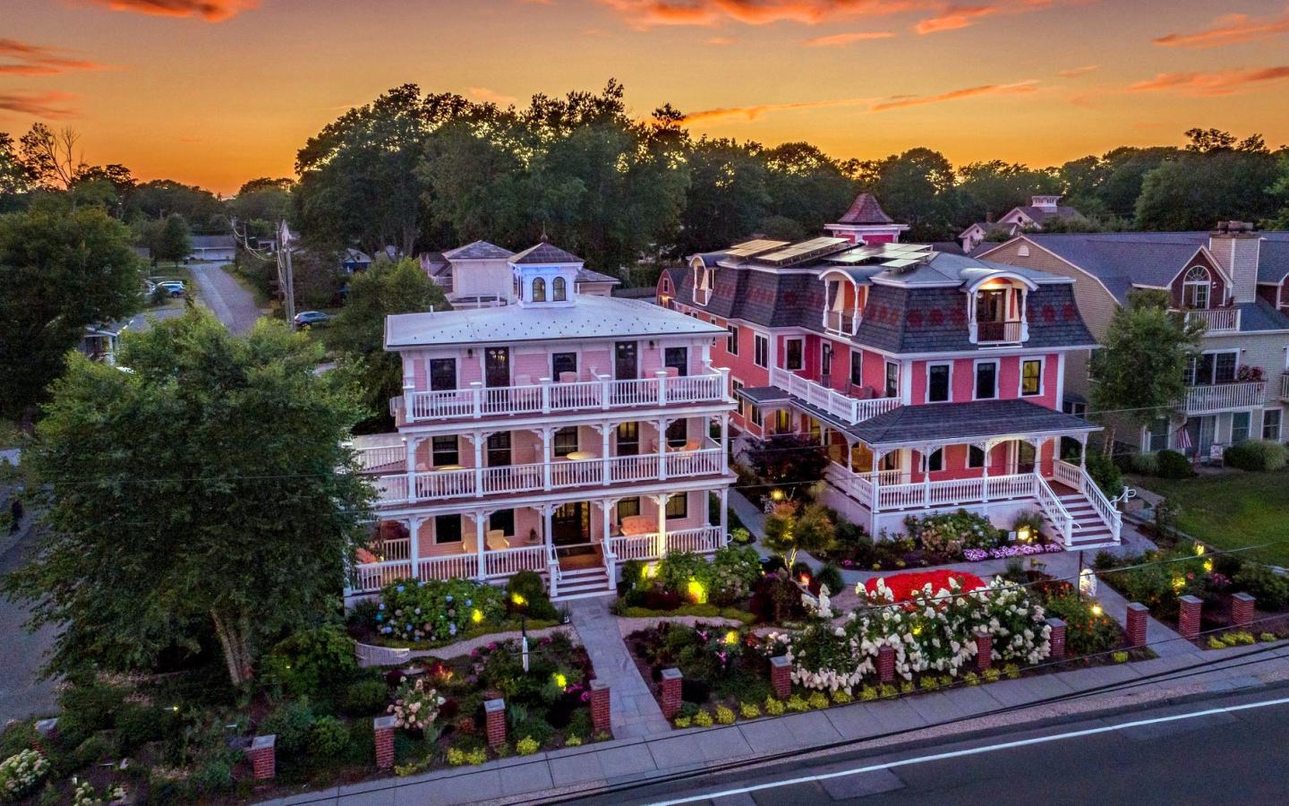 Victorian-style houses at sunset with gardens and lit paths.