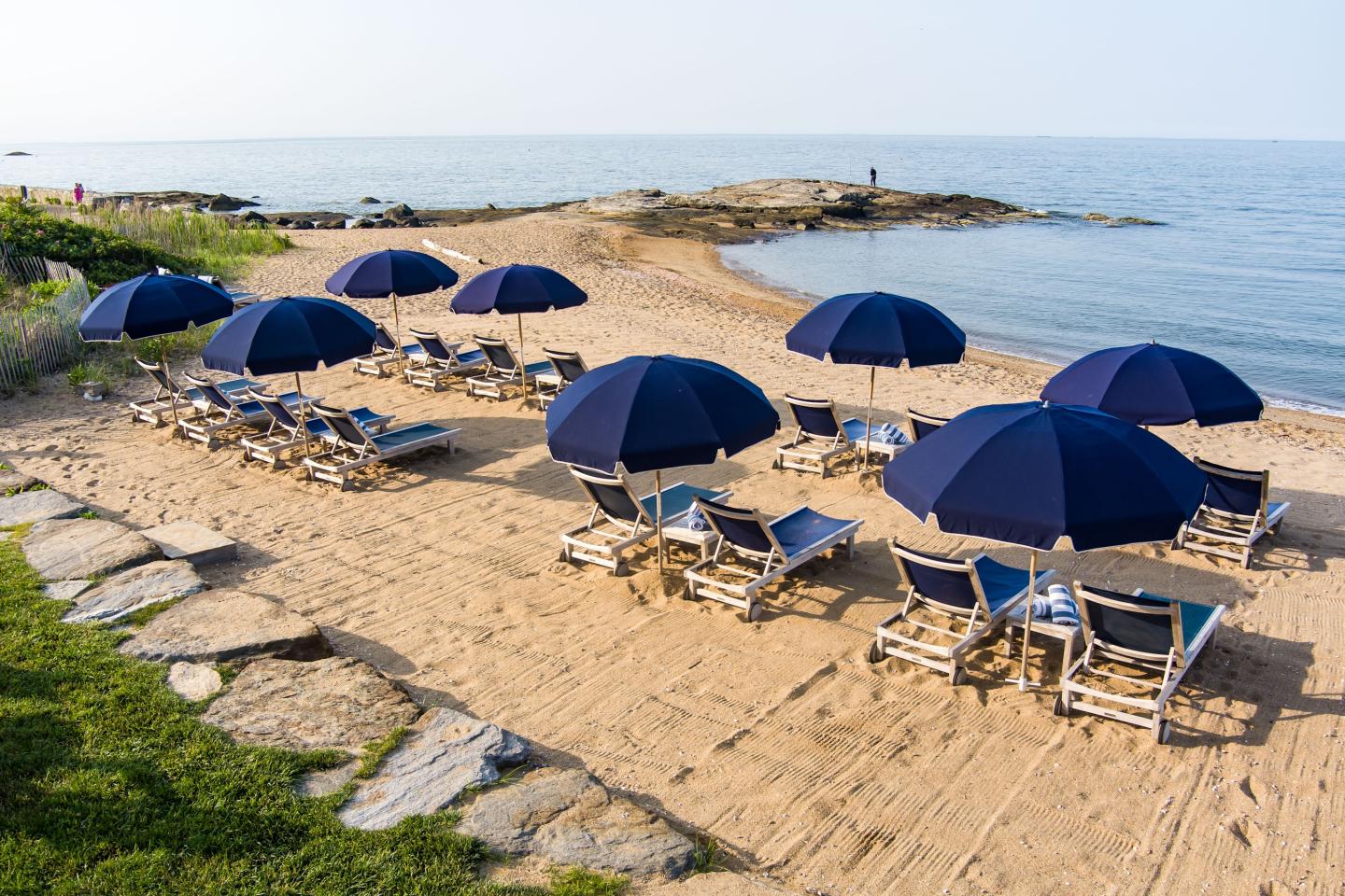 Beach with blue umbrellas and chairs facing the sea.