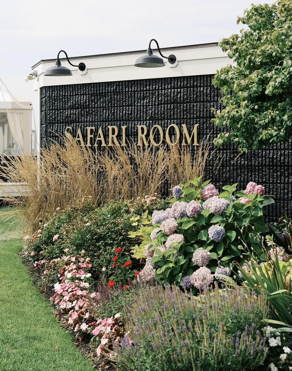 Garden with hydrangeas and flowers in front of a black wall with "SAFARI ROOM" text.