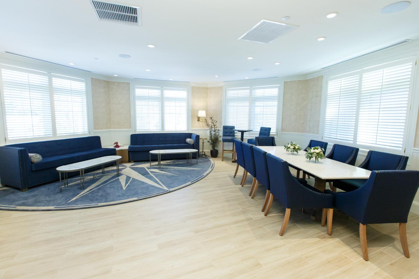 Spacious room with blue sofas, dining table, and natural light.