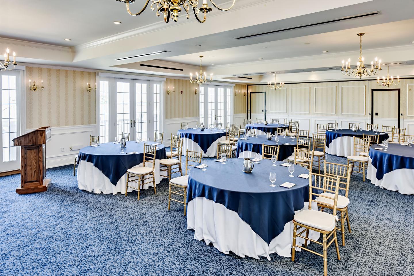 Elegant banquet hall with blue tablecloths and chandeliers.