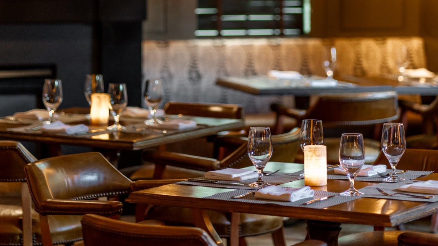 Cozy restaurant with candlelit tables and leather chairs.