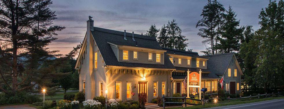 Cozy inn at dusk with warm lights and a serene garden.
