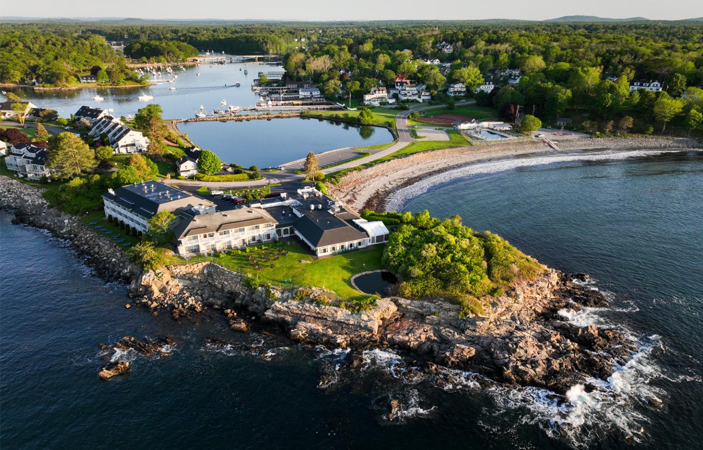 Clifftop resort by the sea, lush greenery, and rocky shoreline.