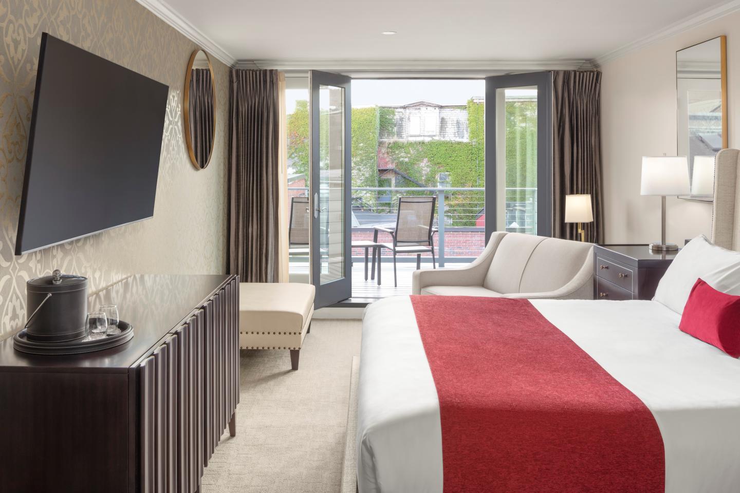 Modern hotel room with balcony doors open, large bed, and flat-screen TV.