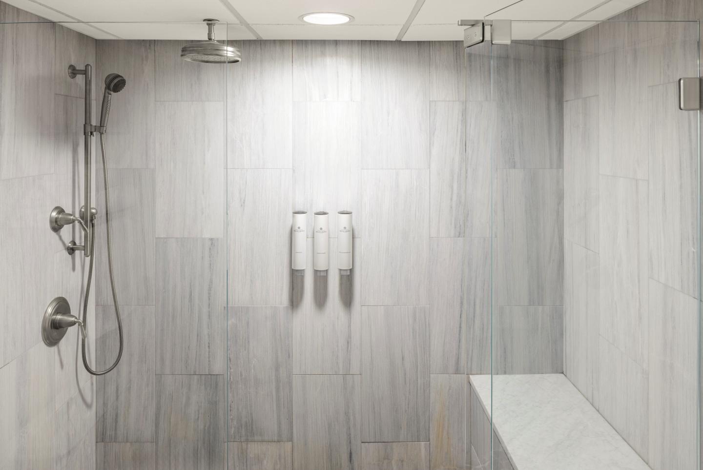 Modern tiled shower with dual showerheads and a built-in bench.