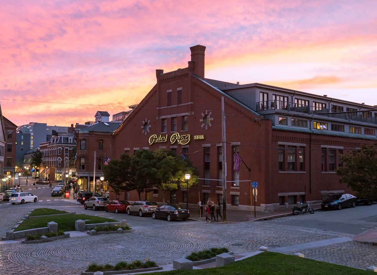Historic red brick building at sunset, city street in foreground.