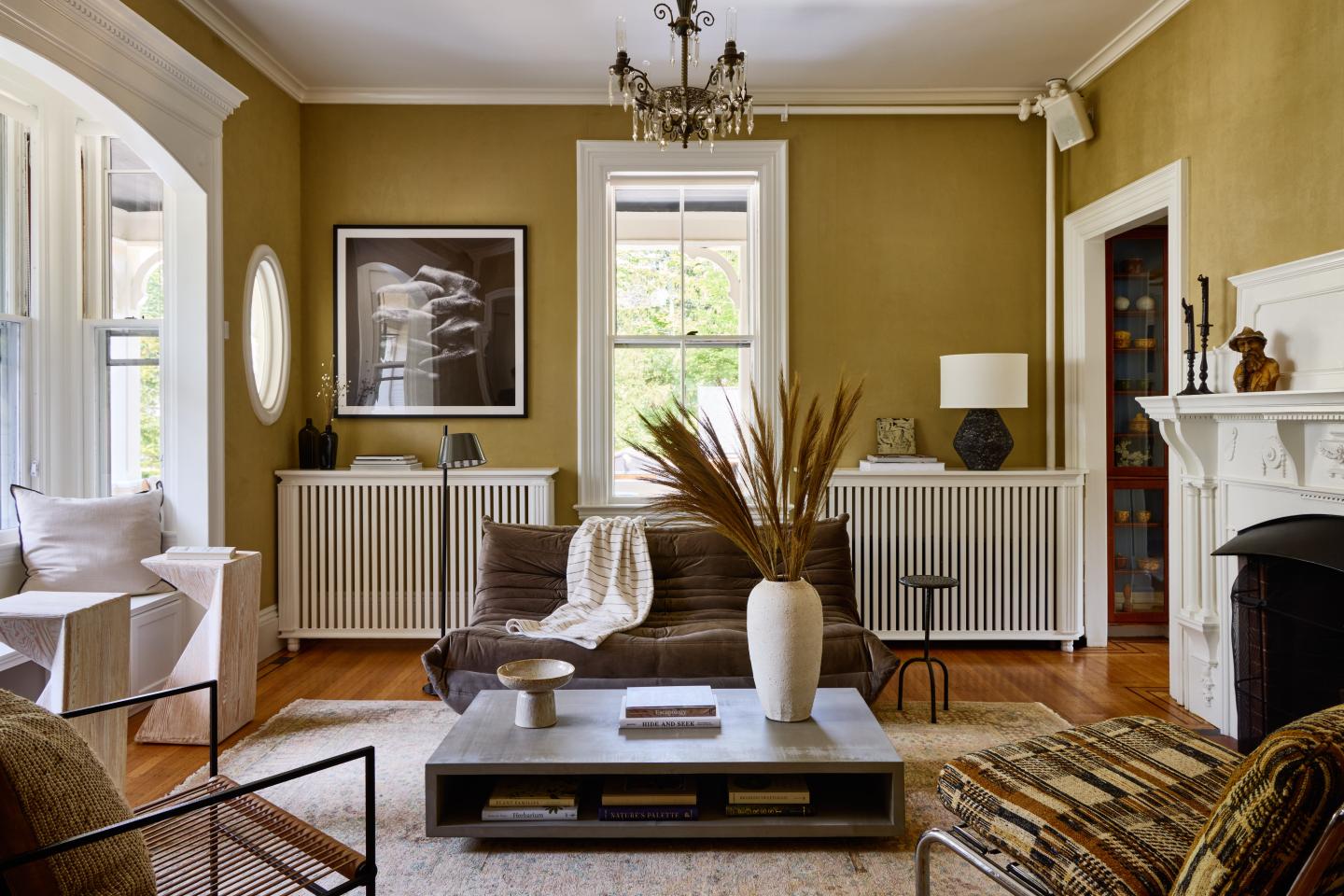 Elegant living room with brown sofa, modern art, and large vase on a coffee table.