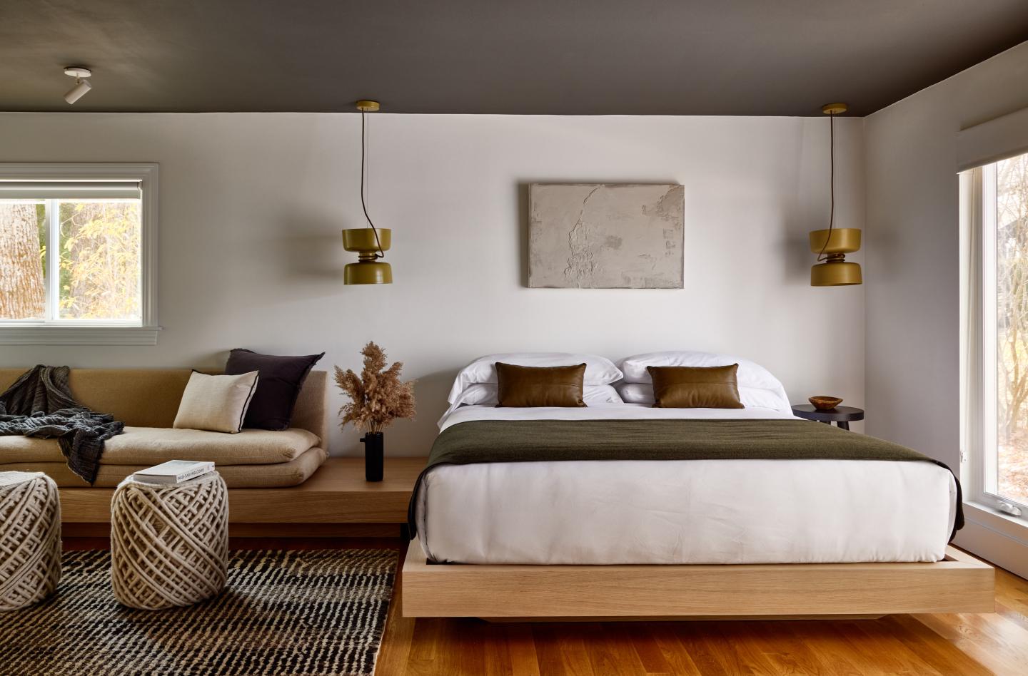 Modern bedroom with bed, sofa, and warm lighting.