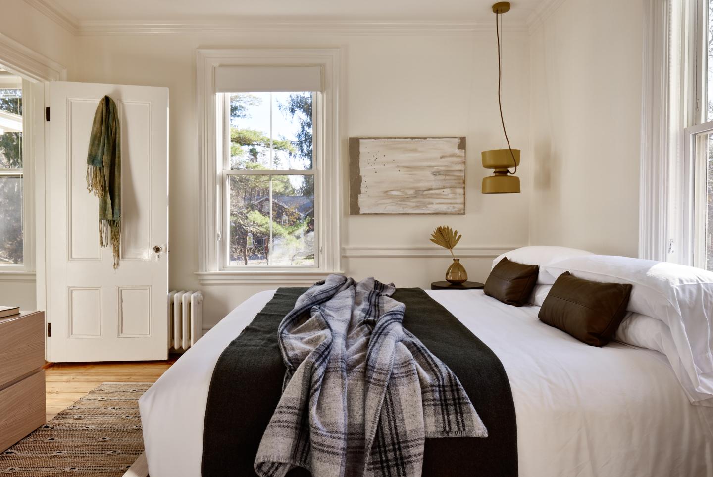 Cozy bedroom with a bed, pillows, throw blanket, and soft lighting.