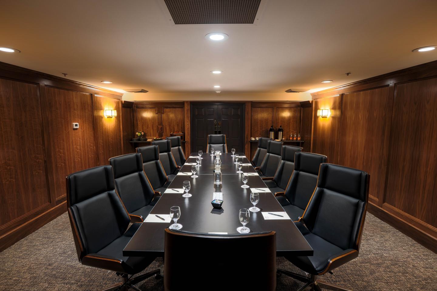 Elegant conference room with a long table, chairs, and dim lighting.